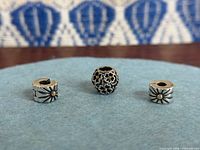 Front view of three Pandora charms on felt background