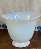 Opaque white pedestal glass bowl on wooden surface
