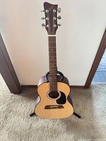Full view of First Act acoustic guitar on stand