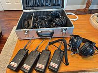 Full lot showing four radios, three headsets, aluminum case