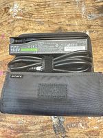 Adapter label showing Sony branding, 19.5V rating, cord coiled, pouch interior