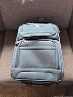 Front view of blue softside suitcase showing exterior pockets and brand plaque