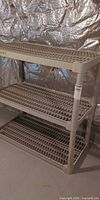 Full view of beige three-shelf plastic shelving unit showing overall design and condition