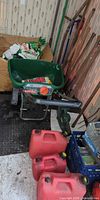 Overall lot with spreader, gas cans, long-handled tools, bags of fertilizer