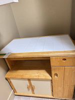 Front and top view showing tile surface, drawer, cabinet doors, shelf