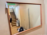 Front view of rectangular wood-framed mirror mounted on wall