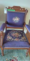 Full front view of chair showing carved wood frame and floral needlepoint