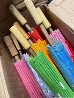 Top view of parasols packed in carton showing wooden handles and assorted coloured folded canopies