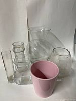 Group of five clear glass vases and pink plant pot
