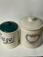 Front view of both ceramic canisters showing lids and graphics