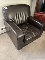 Front-left view of dark brown leather armchair showing overall style and wear