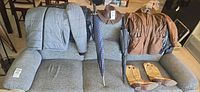 Overview of all items on sofa: jackets, vest, umbrellas, hat, boots