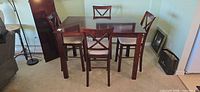 Square dark wood dining table with four matching chairs