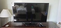 Front view of LG 42" TV on stand with remotes visible