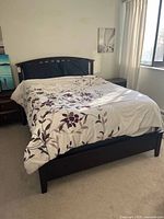 Front view of queen bed showing mattress and full wood frame