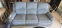 Front view of gray three-seat recliner sofa, cushions and upholstery visible