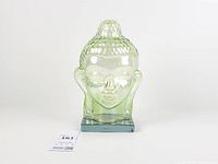 Front view of pale green iridescent glass Buddha head on square glass base
