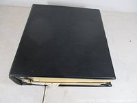 Closed black binder showing thickness of contents