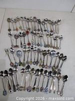 Full layout of approximately 63 souvenir spoons and fork