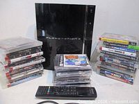 PlayStation 3 console vertical with remote and stacks of games