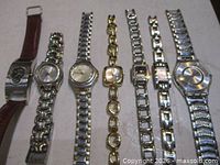 Seven wristwatches laid out side-by-side showing fronts and bracelets