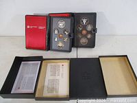 Both proof sets opened to show coins, certificates and outer boxes