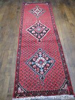 Full view of red Persian runner rug on wooden floor