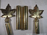 Two brass maple leaf finials and two brass couplers displayed front view