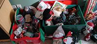 Overview of two totes with assorted Christmas decorations including ceramic tree, plush figures, ornaments and plate