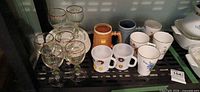 Plates, wine glasses, mugs and steins arranged on shelf