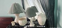Group shot of three Belleek porcelain table lamps and three decorative containers on shelf