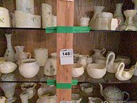 Cabinet shelves filled with Belleek pieces; visible swans, creamers, vases, jars