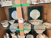 Display cabinet with multiple Belleek basket bowls, commemorative plates and figurines
