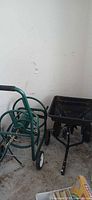 Hose reel cart and push spreader side by side in garage