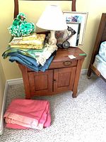 Nightstand top with stacked throws, lamp, clock, framed prints