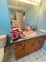 Bathroom vanity showing towels, plush bear, figurines, wooden box, clock, decor