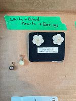Overview showing black pearl pendant, white pearl pendant, and pair of carved flower earrings on card marked 9ct Gold Made in Ireland