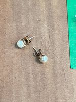 Pair of cultured pearl stud earrings on brown background