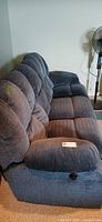 Full side view of blue fabric reclining sofa