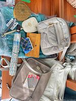 Overview of handbags, wallets, umbrella and compact mirror on table