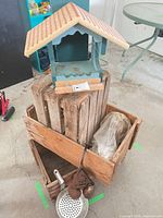 Overall lot showing bird feeder atop stacked crates with chime, strainer and wrapped lamp