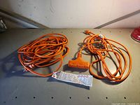 Both orange extension cords coiled on tabletop