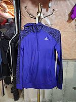 Full view of purple Adidas Climawarm quarter-zip jacket on hanger
