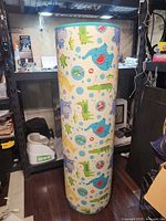 Rolled cylindrical play mat standing upright, shows animal pattern