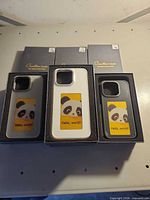 Front view of three cases (white, grey/black) and additional boxed cases behind