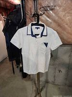 Full view of white JAG polo shirt on hanger showing front, sleeves, collar and contrast trim.
