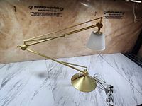 Full view of brass articulating lamp on surface