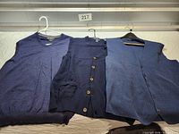 All three blue sweater vests laid out side by side