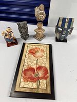 Group view: framed art, mask, owl statue, stone figure, Superman figurine