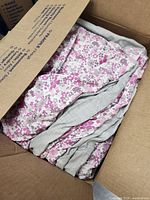 Folded pink and purple floral blankets inside a cardboard box